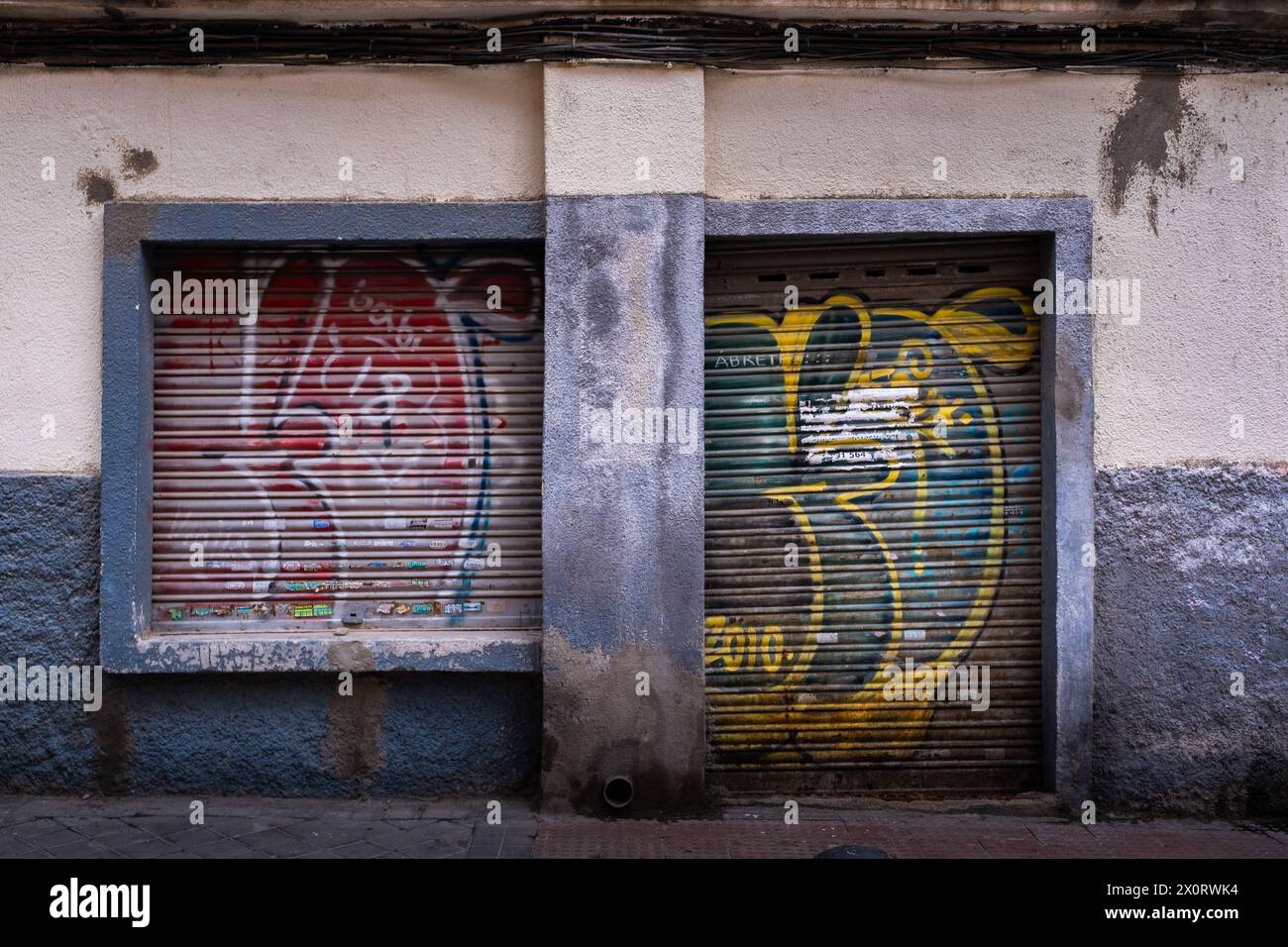 Scène urbaine avec un vieux quartier dans une ville européenne avec un local abandonné au rez-de-chaussée avec de la peinture ancienne et fanée et de vieux graffitis usés par le temps. Banque D'Images