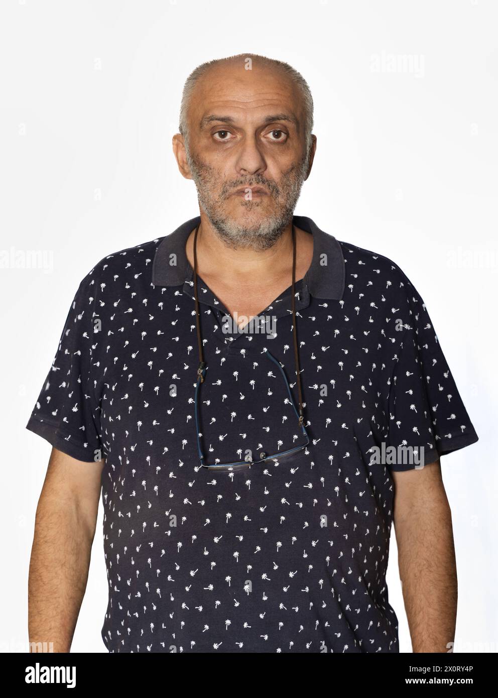 homme caucasien de 55 ans isolé sur fond blanc décontracté habillé avec un t-shirt et des lunettes suspendues sur le cou Banque D'Images