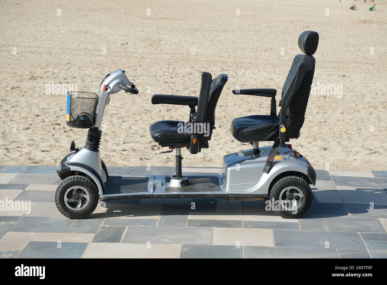 Scooter de mobilité garé sur la route pavée près de la plage de sable le jour ensoleillé Banque D'Images