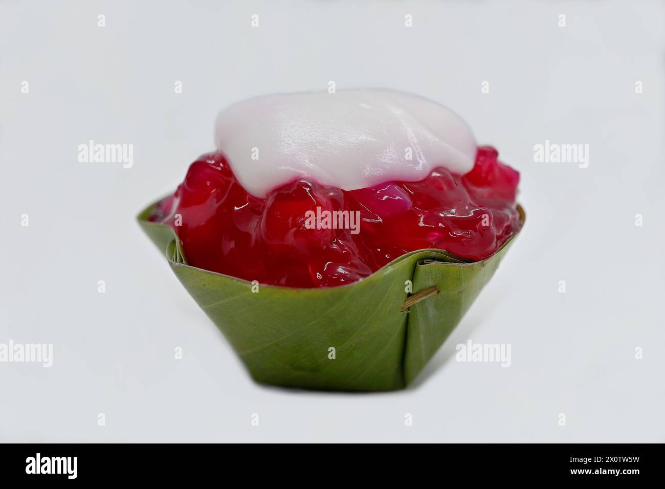 Gros plan d'un dessert thaïlandais Khanom Tako à l'envers, avec des marrons d'eau rubis rouges (Tub Tim Grob) garnitures dans une tasse à feuilles de pandan Banque D'Images