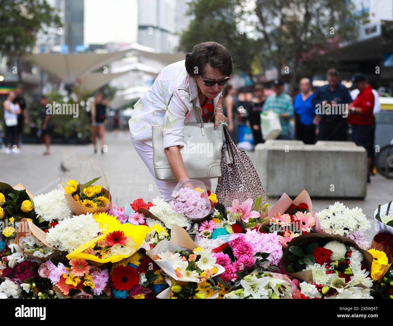 Sydney, Australie. 14 avril 2024. Une femme dépose des fleurs devant le Westfield Shopping Centre à Bondi Junction à Sydney, Australie, le 14 avril 2024. Dimanche, la police australienne a identifié l'auteur d'un attentat à l'arme blanche dans un centre commercial de Sydney qui a tué six personnes, affirmant qu'aucun renseignement ne suggérerait que l'attaque était motivée par une idéologie. L'agresseur de l'attaque de samedi après-midi au Westfield Shopping Centre à Bondi Junction était Joel Cauchi, 40 ans, du Queensland, Nouvelle-Galles du Sud (Nouvelle-Galles du Sud), le commissaire adjoint de la police Anthony Cooke, a déclaré aux journalistes. Crédit : ma Ping/Xinhua/Alamy Live News Banque D'Images