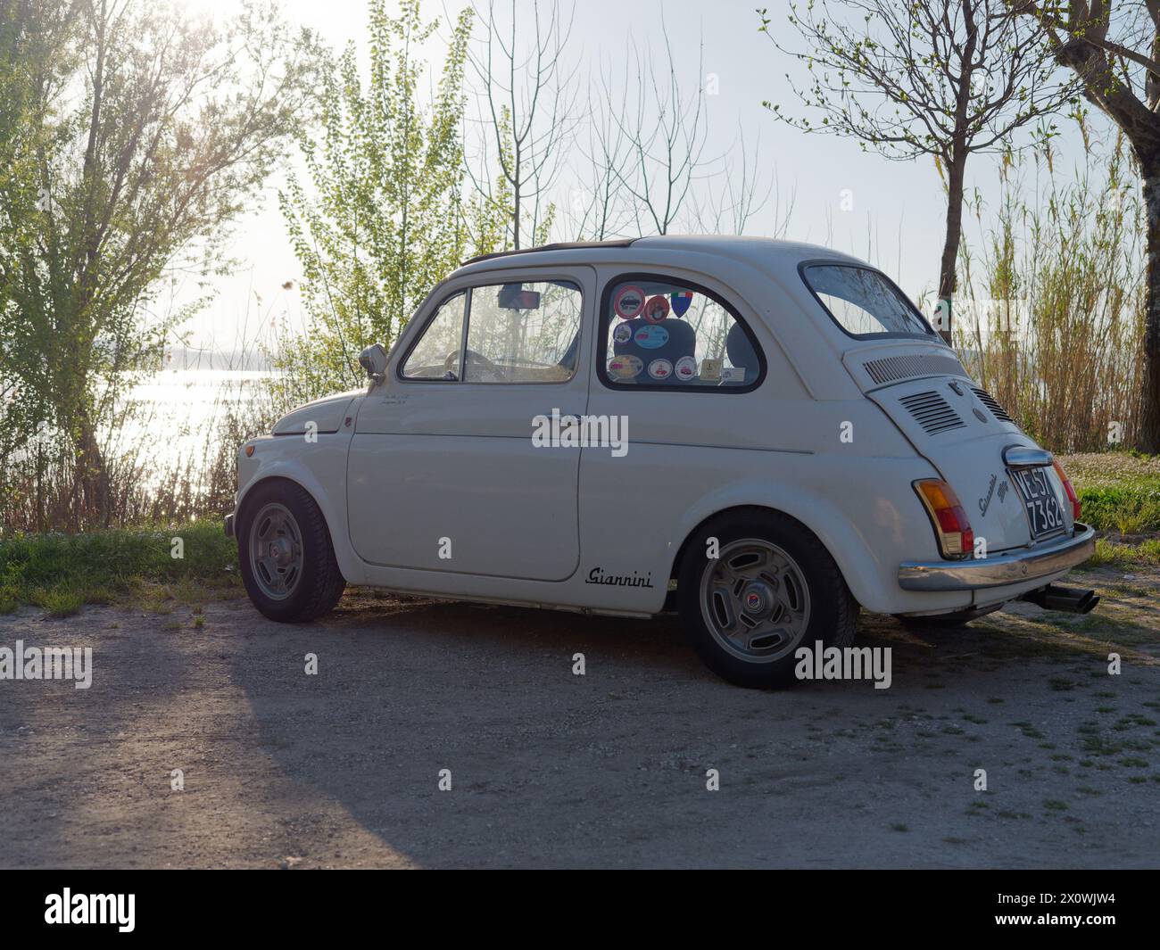 Fiat 500 classique en blanc garé au bord du lac Bolsena près de Montefiascone par une soirée ensoleillée. Province de Viterbe, région du Latium, Italie. 13 avril 2024 Banque D'Images