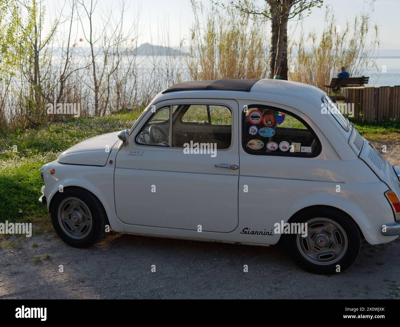 Fiat 500 classique en blanc garé au bord du lac Bolsena près de Montefiascone par une soirée ensoleillée. Province de Viterbe, région du Latium, Italie. 13 avril 2024 Banque D'Images