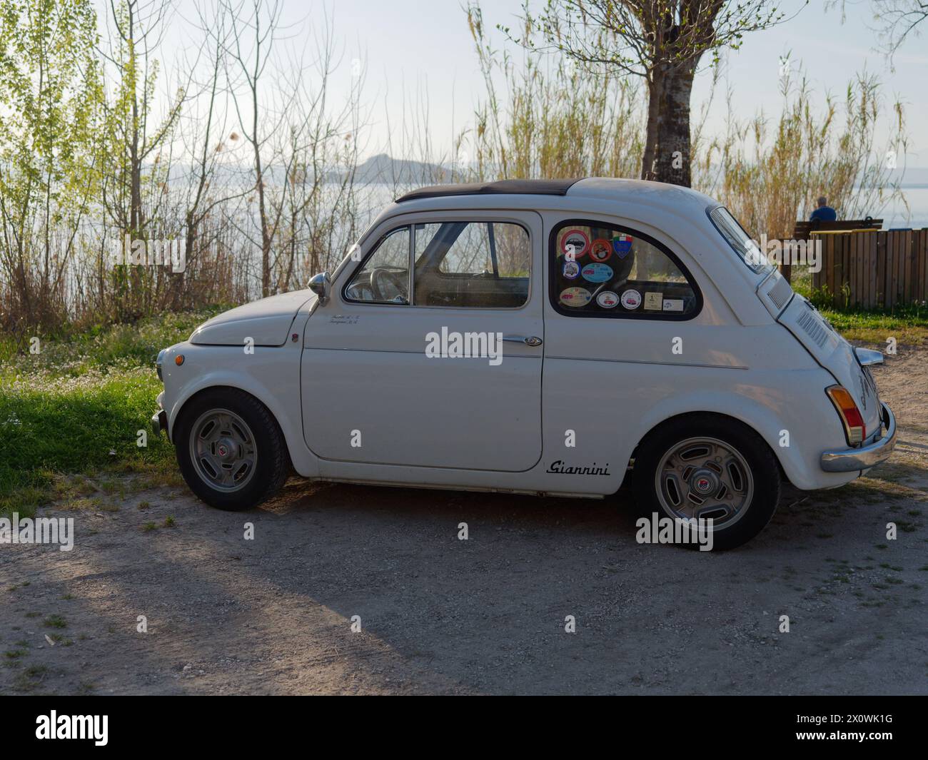 Fiat 500 classique en blanc garé au bord du lac Bolsena près de Montefiascone par une soirée ensoleillée. Province de Viterbe, région du Latium, Italie. 13 avril 2024 Banque D'Images