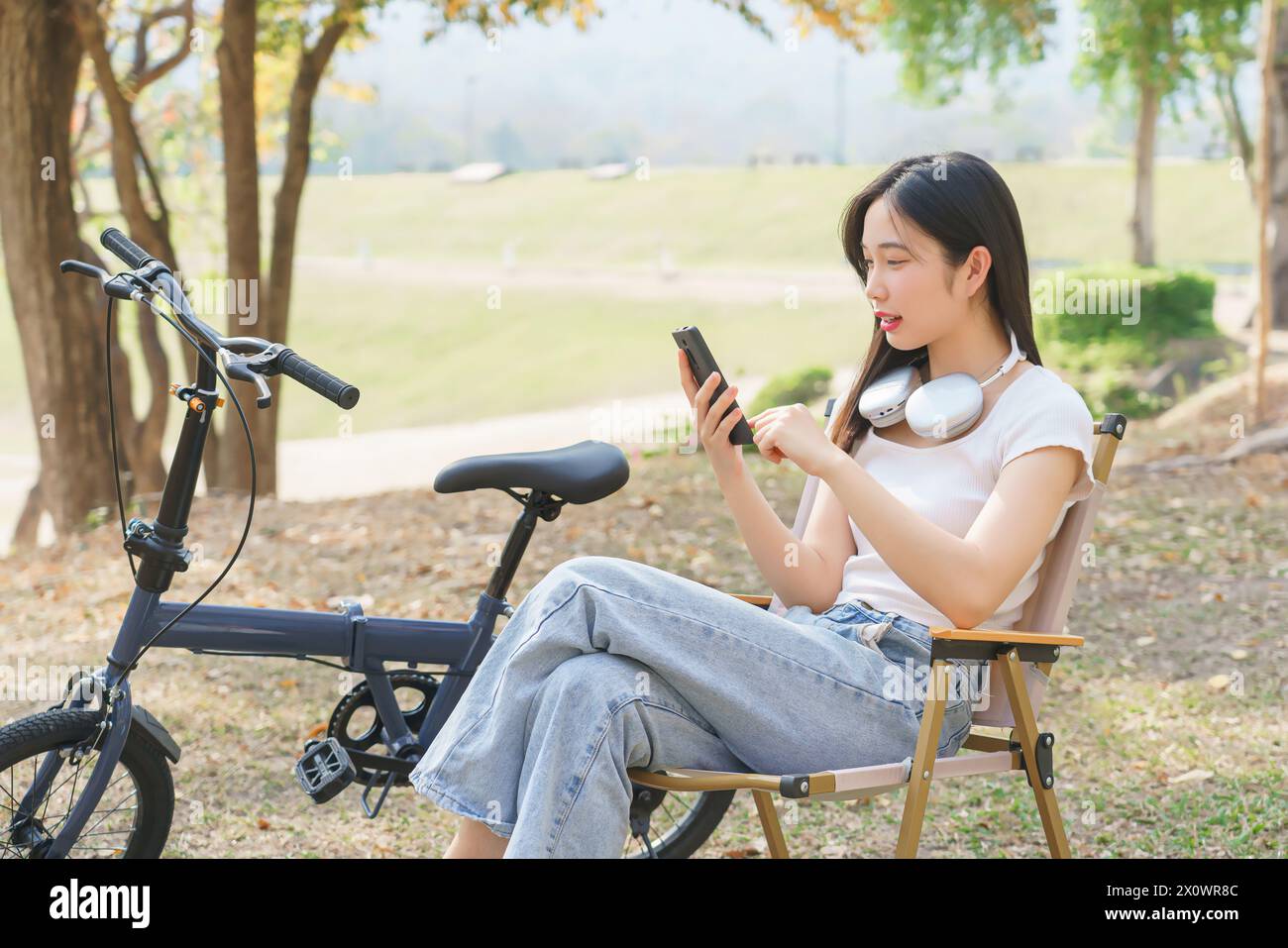 Jeunes femmes asiatiques vérifiant le divertissement des médias sociaux et lisant des messages discutant sur smartphone tout en étant assis sur une chaise pour se détendre avec Journey tra Banque D'Images