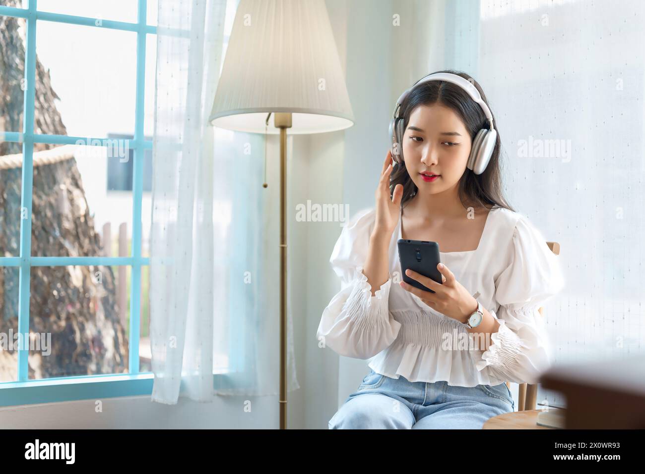 Jeune femme d'affaires asiatique portant casque à écouter de la musique et surfer sur les médias sociaux sur smartphone après la stratégie d'analyse sur l'investissement et pla Banque D'Images