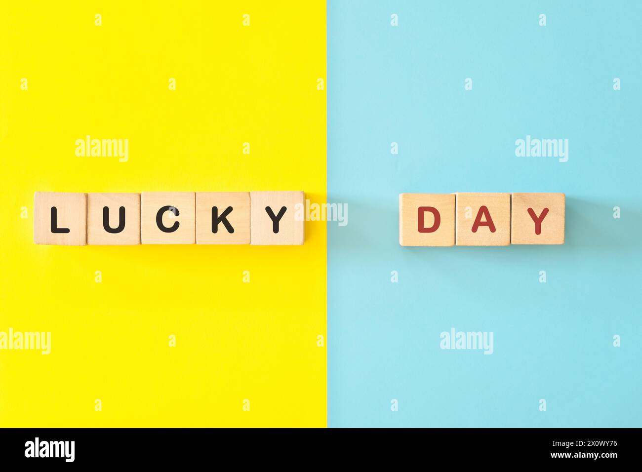 Typographie de blocs en bois Lucky Day en fond bleu et jaune vif. Banque D'Images