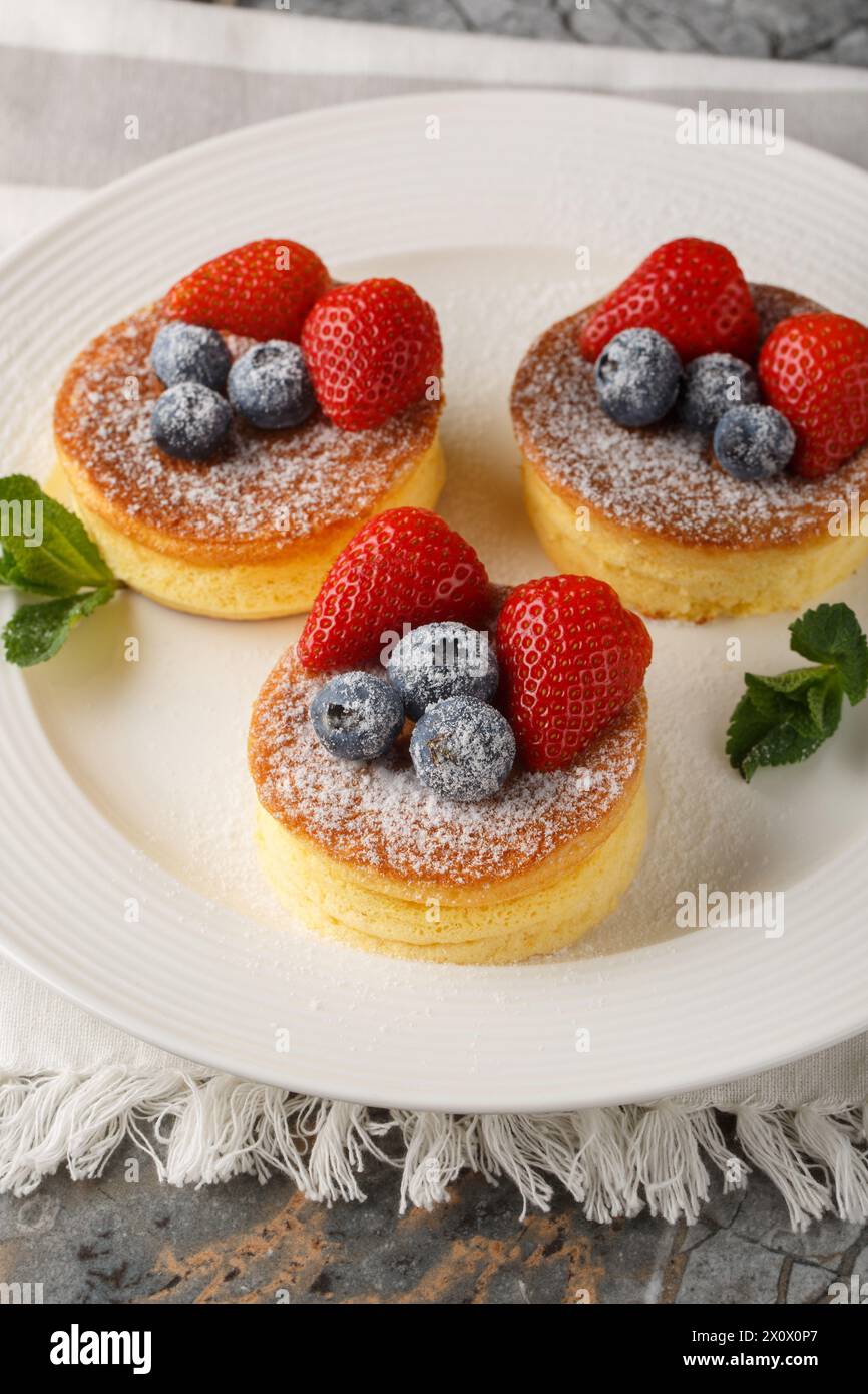 Crêpes japonaises moelleuses avec des baies fraîches gros plan sur une assiette sur la table. Vertical Banque D'Images