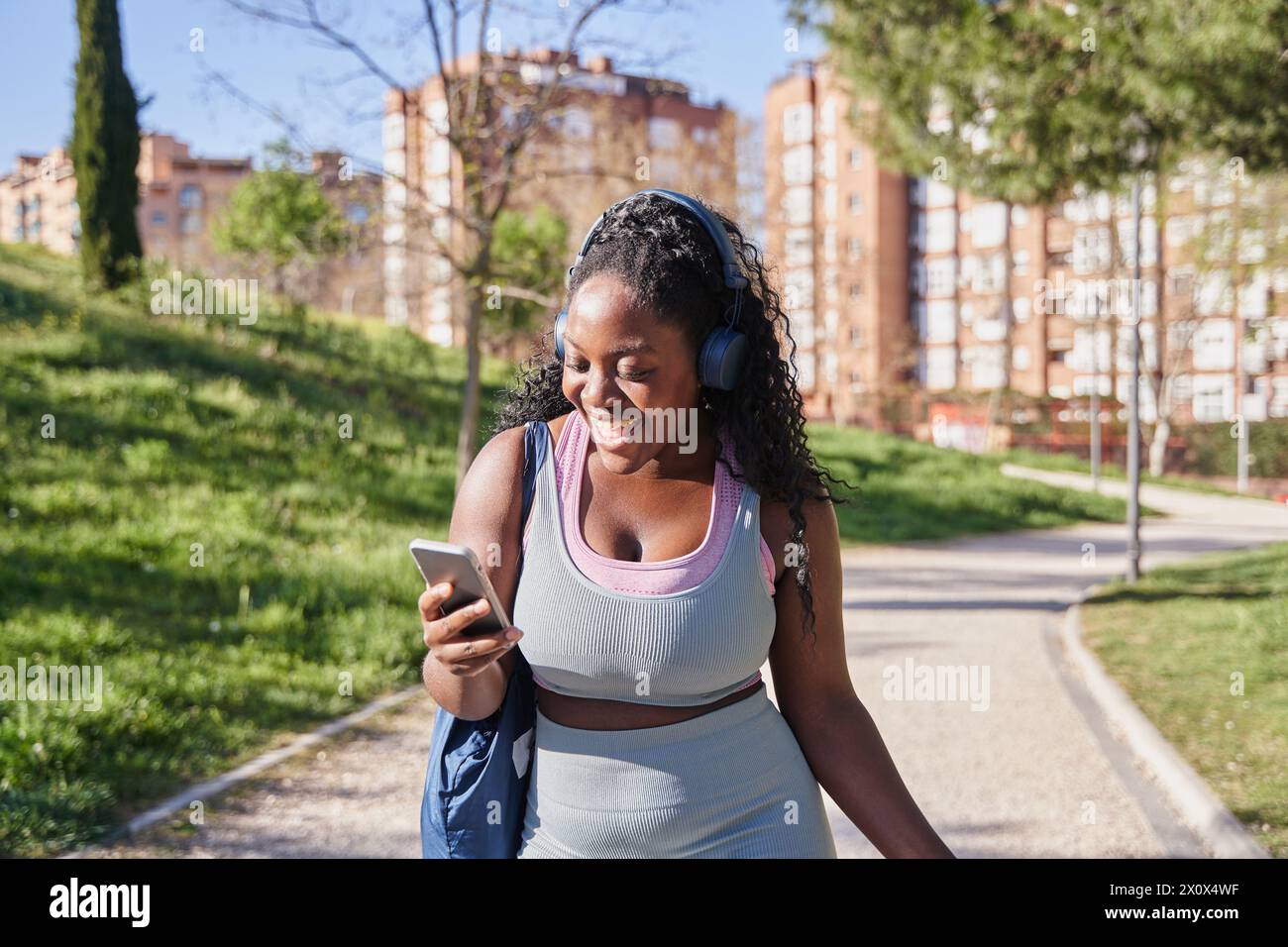 souriante jeune femme active dans les vêtements de sport courir jog sur le parc utilisez un appareil de téléphone portable moderne. Joyeux millennial ou gen z fit femme coureuse Browse smartphone WO Banque D'Images
