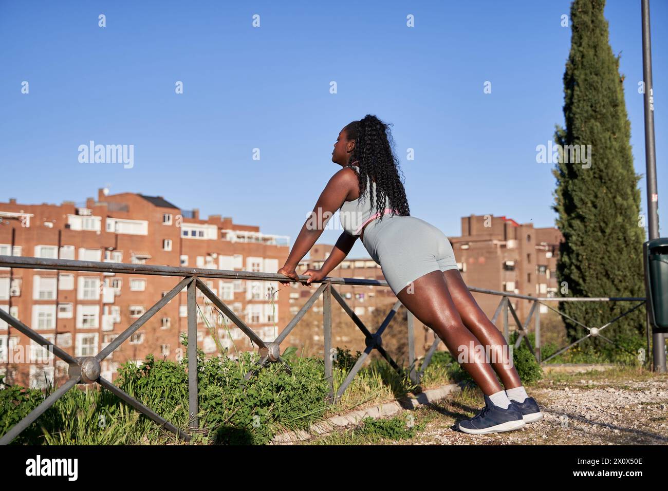 Vue arrière femme afro-américaine fitness dans les vêtements de sport faisant push up sur la clôture à l'extérieur Banque D'Images