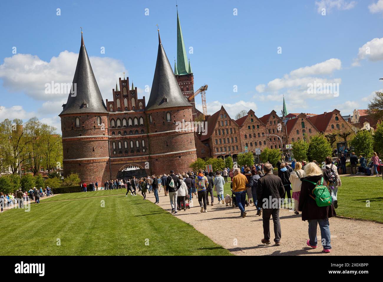 14 avril 2024, Schleswig-Holstein, Lübeck : de nombreuses personnes se sont rassemblées sur la Holstentorplatz devant l'Holstentor. En raison du vent fort, une action de l’artiste Stephanie Lüning prévue en début d’après-midi a été reportée au soir. Lünning voulait inonder la place devant l'Holstentor de mousse dans le cadre de l'exposition « Hello Lübeck ». Elle a déjà mené des actions similaires au Centre Pompidou à Paris et dans des espaces publics à Londres. L'action est le prélude à l'exposition en transition à la Kunsthalle préparée Annen. Photo : Georg Wendt/dpa Banque D'Images