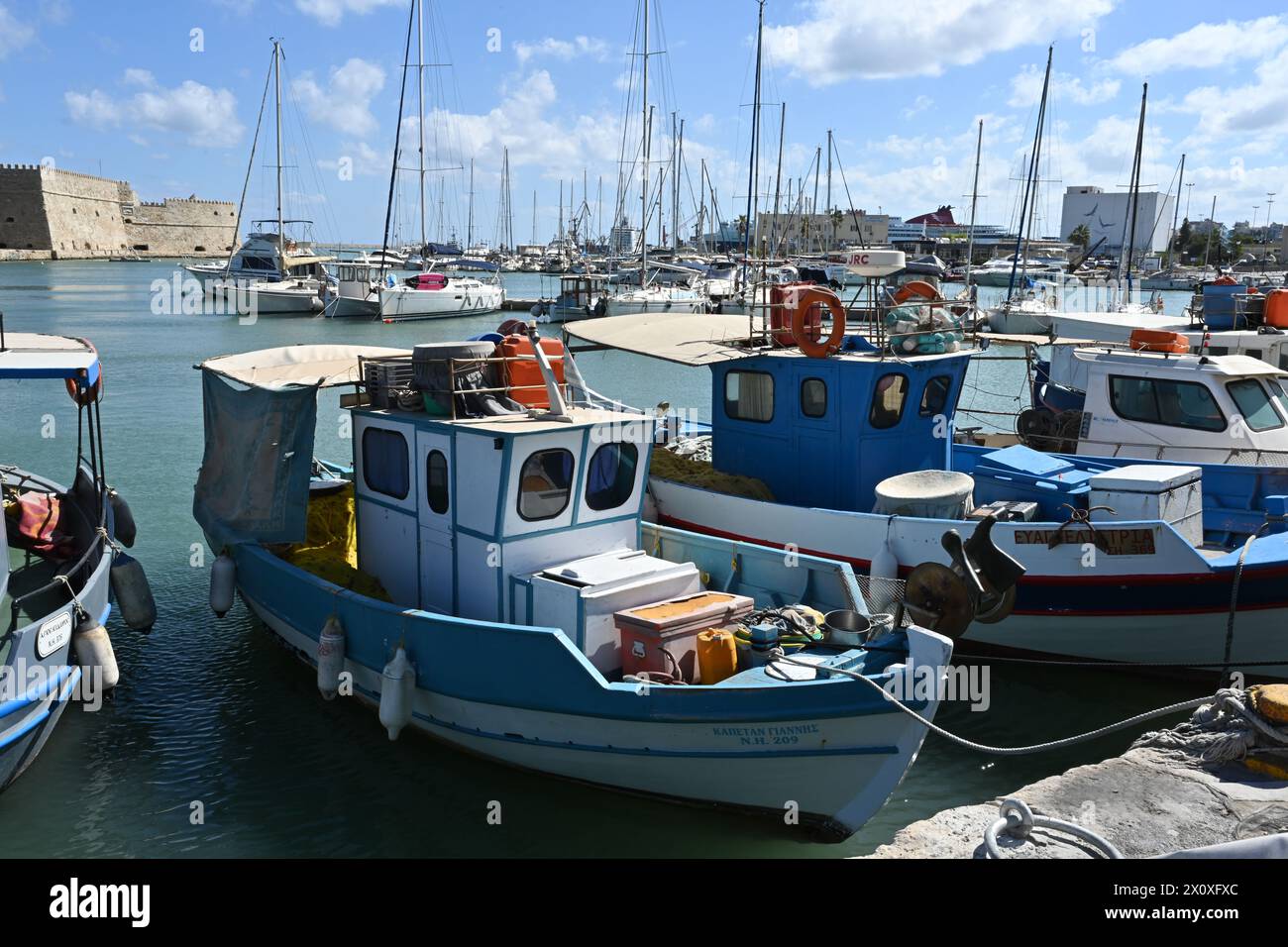 Vieux bateaux de pêche grecs en bois avec des coques blanches et bleues dans le port d'Héraklion près du centre-ville pendant l'été. Banque D'Images