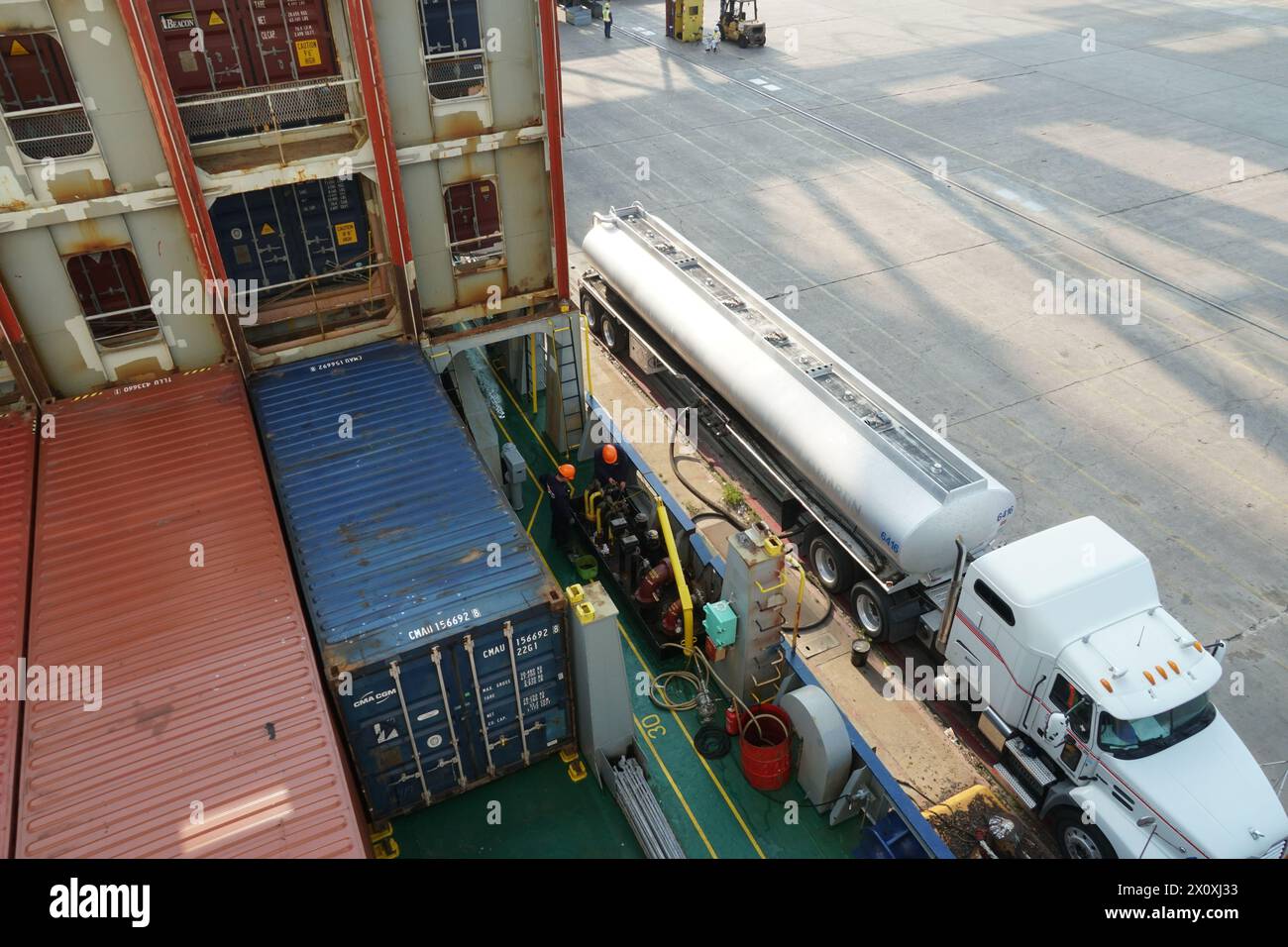 Une vue du tuyau de carburant s'étendant du camion-citerne au navire porte-conteneurs au poste de soute. Banque D'Images