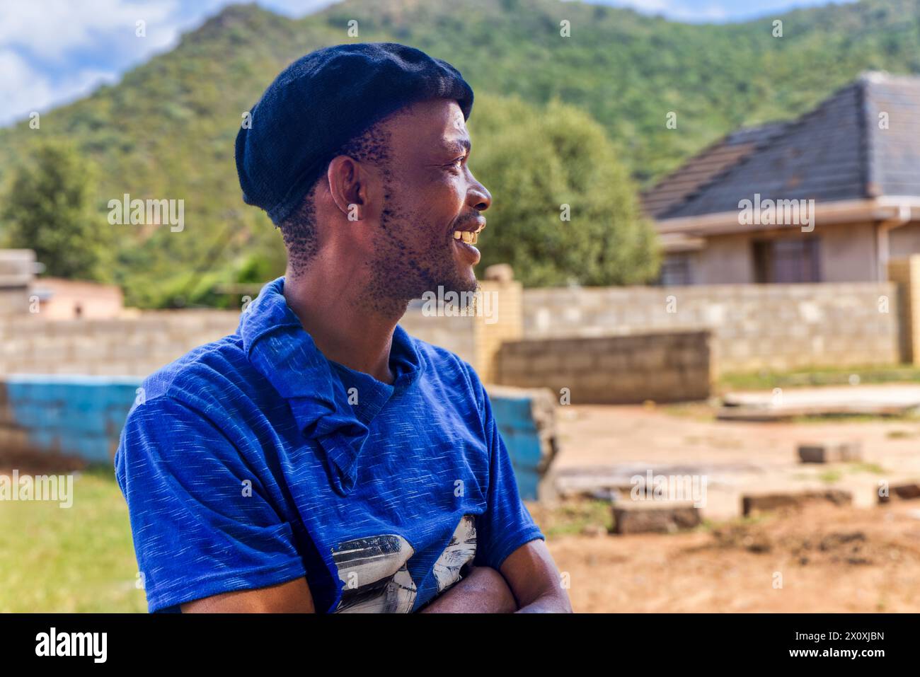 village jeune homme africain debout devant la maison dans la cour , vue de profil, Banque D'Images