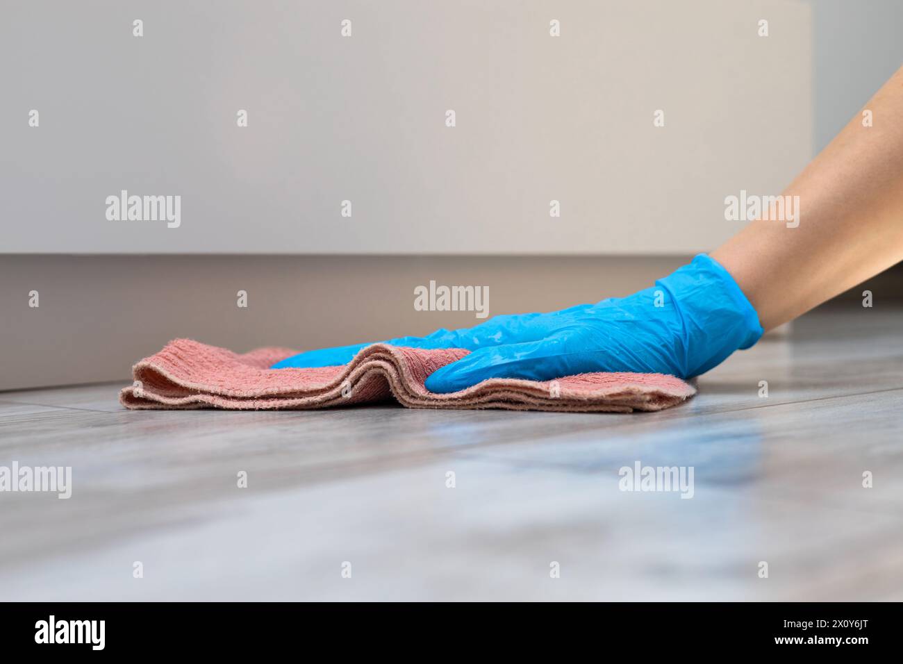 femme au foyer en gants de caoutchouc lave le sol à la maison. femme faisant le nettoyage humide à la maison. l'homme lave le sol près du placard. Banque D'Images