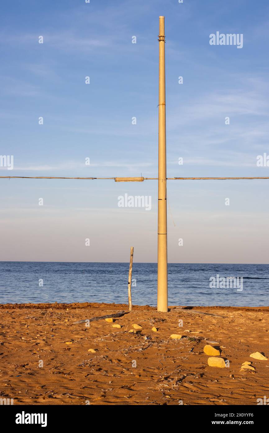 Au moment du lever du soleil, le sable sur la plage colorée en or. Mer Méditerranée. Ciel bleu avec des nuages légers. Colonne électrique avec cabine horizontale Banque D'Images