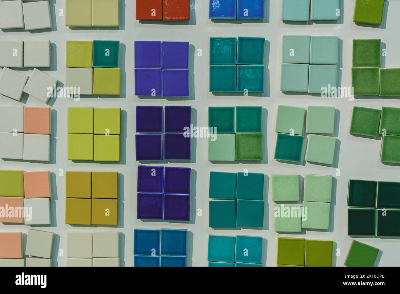 Des dizaines de petits carreaux de céramique de différentes couleurs sont disposés sur un fond blanc Banque D'Images