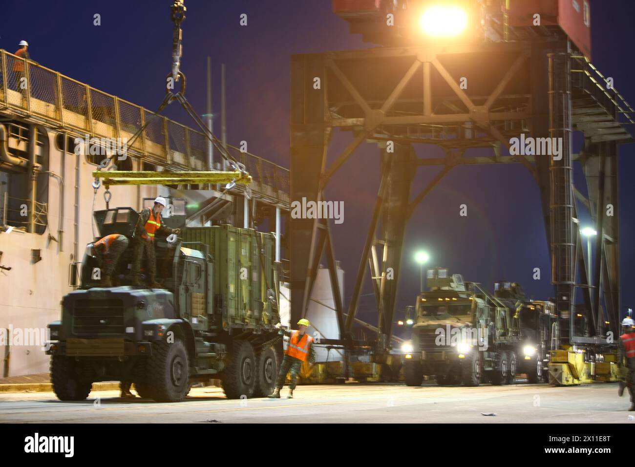 Travaillant jusque dans la nuit, les logisticiens de la 22e unité expéditionnaire des Marines préparent des véhicules pour être hissés sur des navires d'assaut amphibies au port de Morehead City, en Caroline du Nord, le 15 janvier 2010. La 22e MEU se déploiera dans la nation caribéenne ravagée par le tremblement de terre d'Haïti à bord de l'USS Bataan, carter Hall et Fort McHenry pour mener une assistance humanitaire en mer et des secours en cas de catastrophe. Banque D'Images