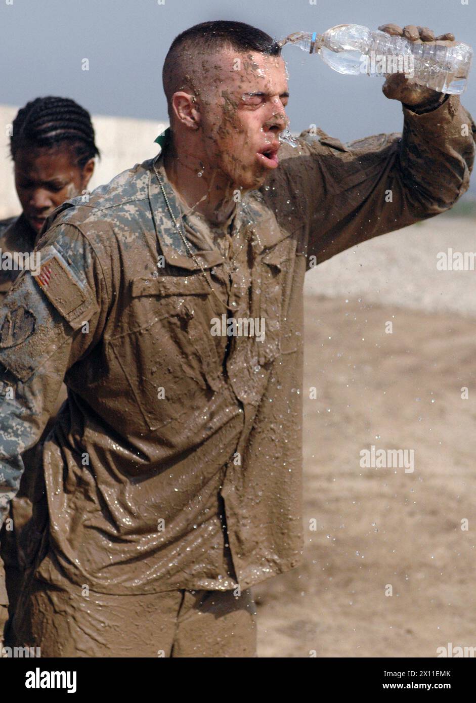 Légende originale : PFC Andrew Crosby, mécanicien de véhicules à roues, E Troop, 2nd Squadron, 6th Cavalry, la 25e division d'infanterie de la brigade de l'aviation de combat, éclabousse l'eau sur son visage après avoir terminé la descente dans la boue pour le traditionnel 'Spur ride' tenu à FOB Warrior, CA. 03 juillet 2004 Banque D'Images