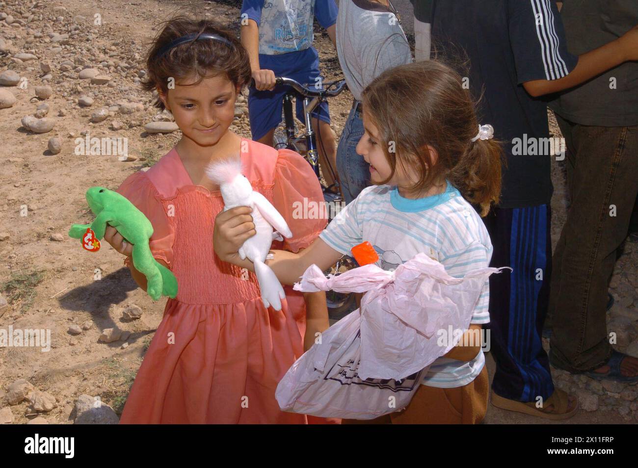 Deux filles irakiennes d’Al Kush, en Irak, un village situé à environ 50 km de Mossoul, regardent les nouveaux bonnets qu’elles ont reçus des soldats du 416e Bataillon des affaires civiles, une unité de réserve de l’armée de Norristown, PA, CA. Juillet 2004 Banque D'Images