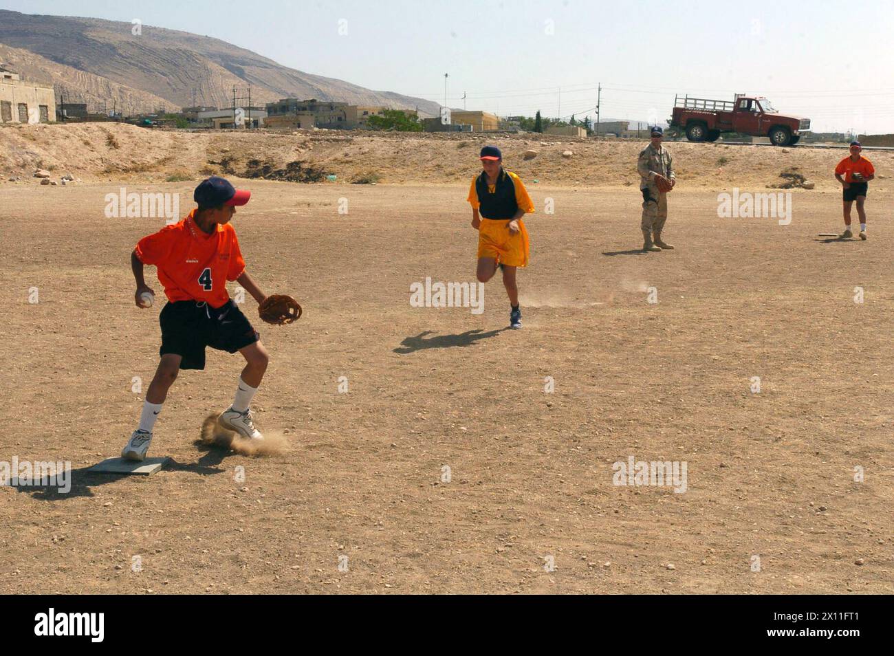 Un jeune irakien attrape un ballon à la deuxième base pour faire le premier match de la journée lors d'un match de baseball avec des soldats du 416e Bataillon des affaires civiles, une unité de réserve de l'armée de Norristown, en Pennsylvanie. Les 416e soldats apprennent aux enfants d'Al Kush, en Irak, un village situé à environ 50 km de Mossoul, à jouer au baseball CA. 29 juillet 2004 Banque D'Images