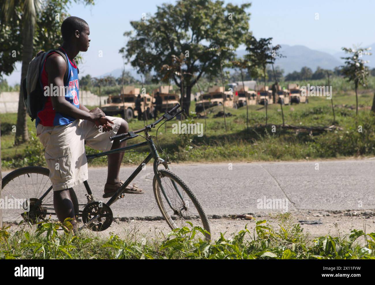 Un homme haïtien regarde alors que les Marines de l'équipe de débarquement du bataillon, 3e bataillon, 2e régiment de Marines, 22e unité expéditionnaire des Marines, se préparent à mener une mission de ravitaillement dans un petit village près de Léogane, Haïti, le 22 janvier 2010. Banque D'Images