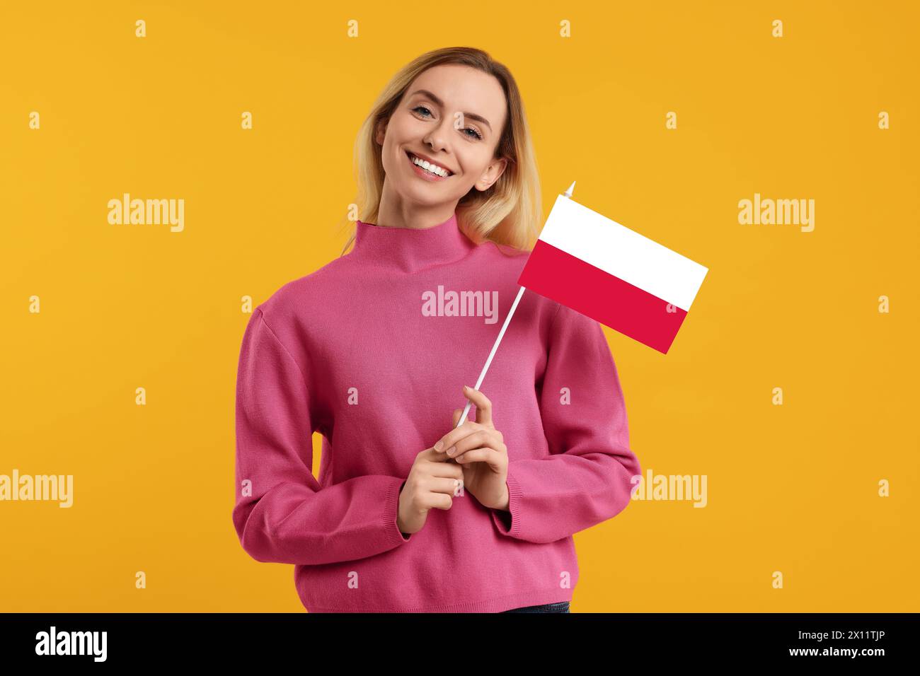 Heureuse jeune femme avec drapeau de la Pologne sur fond jaune Banque D'Images