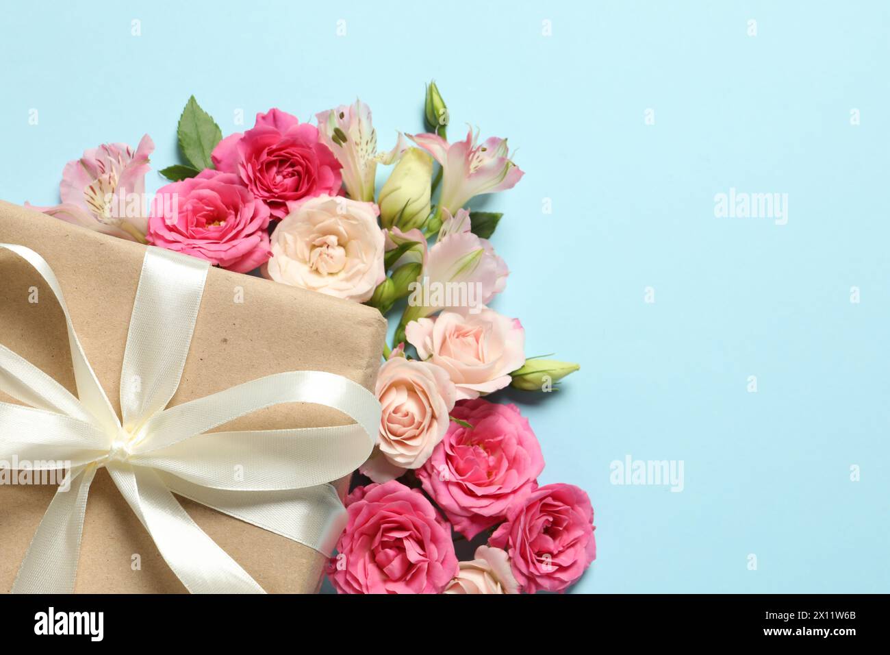 Bonne fête des mères. Belles fleurs et boîte-cadeau sur fond bleu clair, plat. Espace pour le texte Banque D'Images