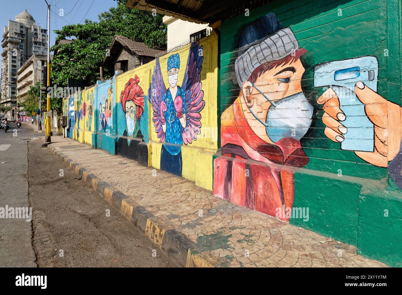 Un mur dans la région de Byculla, Mumbai, Inde, décoré de peintures murales sur le thème du COVID-19, dans l'un d'entre eux, une femme dont la température corporelle a été prise avec un appareil portable Banque D'Images