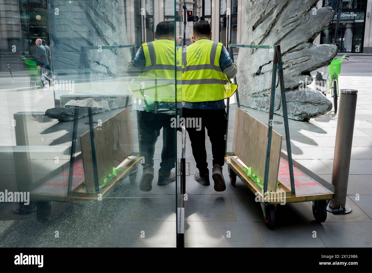 Les entrepreneurs poussent une charge devant la sculpture intitulée 'City Wing' sur Threadneedle Street dans la ville de Londres, le quartier financier de la capitale (alias Square Mile), le 14 avril 2024, à Londres, en Angleterre. City Wing est de l'artiste Christopher le Brun. La sculpture en bronze de dix mètres de haut a été réalisée par Christopher le Brun, président de la Royal Academy of Arts, commandé par Hammerson en 2009. Elle est appelée « The City Wing » et a été moulée par Morris Singer Art Founders, réputée être la plus ancienne fonderie d’art au monde. Banque D'Images