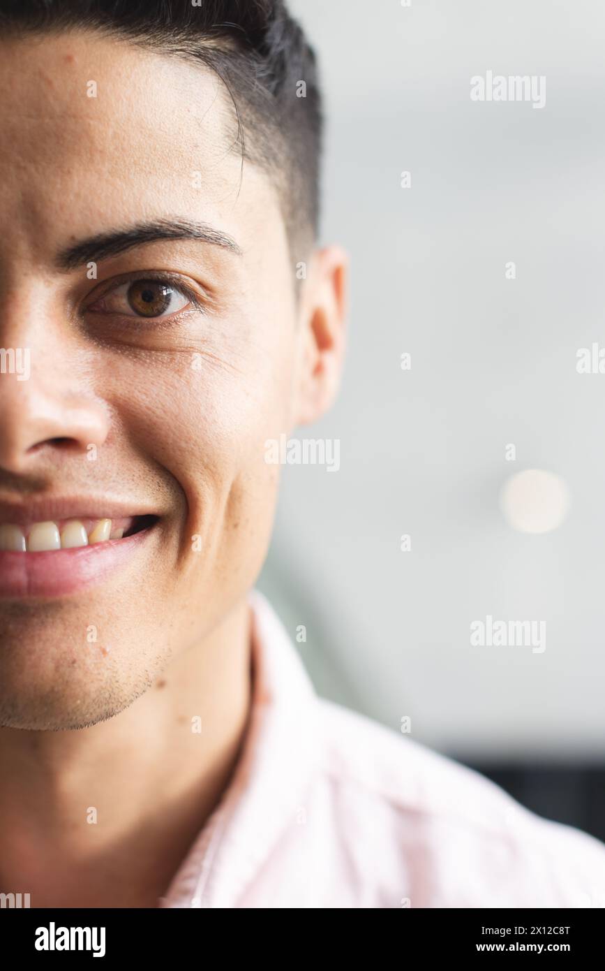 Un jeune homme biracial avec les yeux bruns souriant dans un bureau d'affaires moderne avec espace de copie Banque D'Images