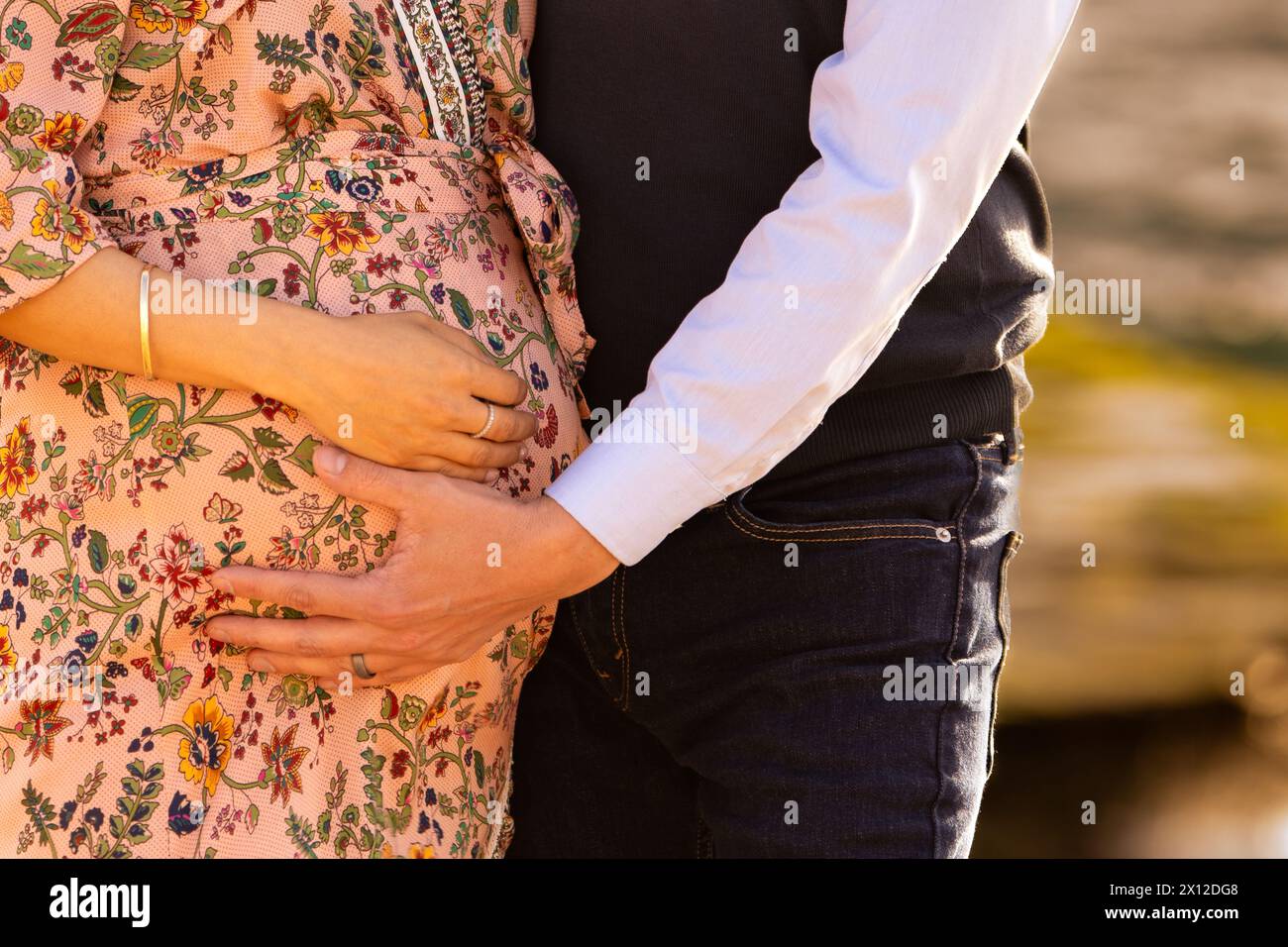 Gros plan d'un ventre enceinte avec les mains de maman et papa dessus Banque D'Images