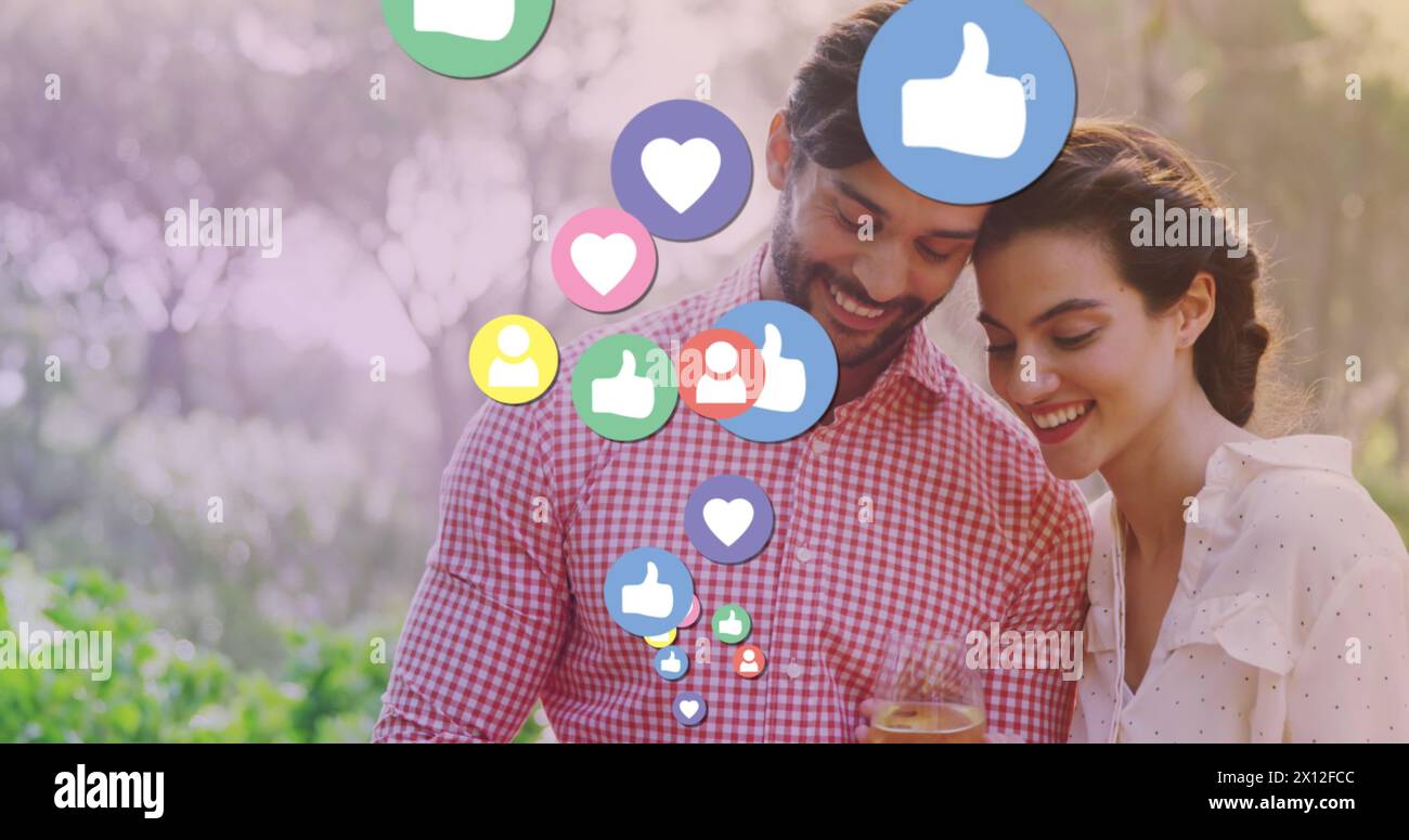 Image d'icônes de médias sur couple biracial heureux à l'aide d'un smartphone Banque D'Images