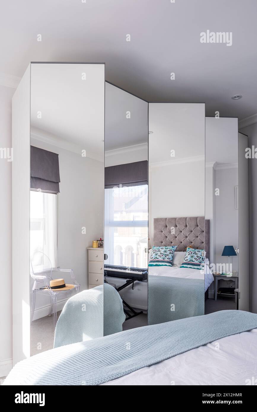 Armoires à miroirs reflétant le lit dans London Flat, Royaume-Uni Banque D'Images