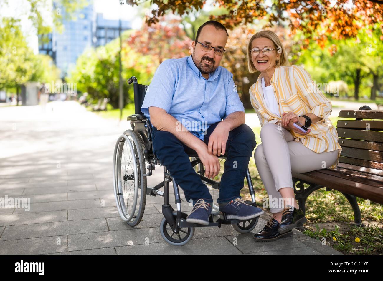 L'homme en fauteuil roulant passe du temps avec sa mère dans le parc. Banque D'Images