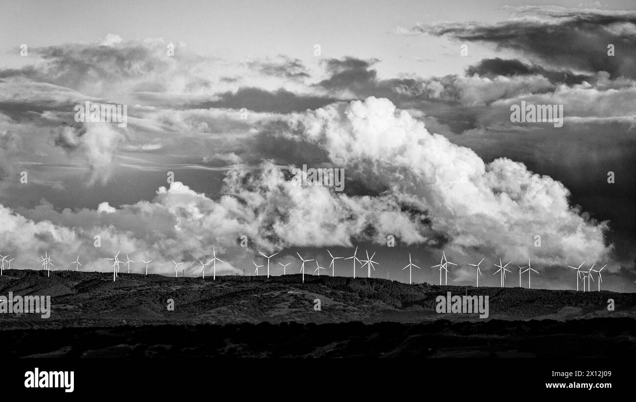 Plusieurs éoliennes sur le bord d'une colline, tandis que dans le fond des nuages inquiétants se forment Banque D'Images