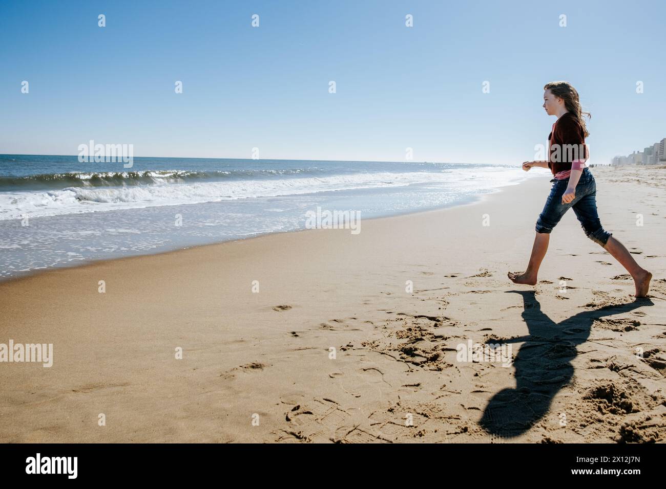 Tween fille marchant vers l'océan le jour ensoleillé Banque D'Images