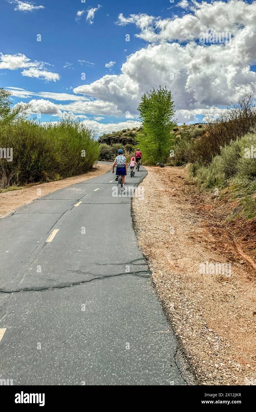 Famille profitant d'une balade à vélo sur un sentier ensoleillé du parc du désert. Banque D'Images