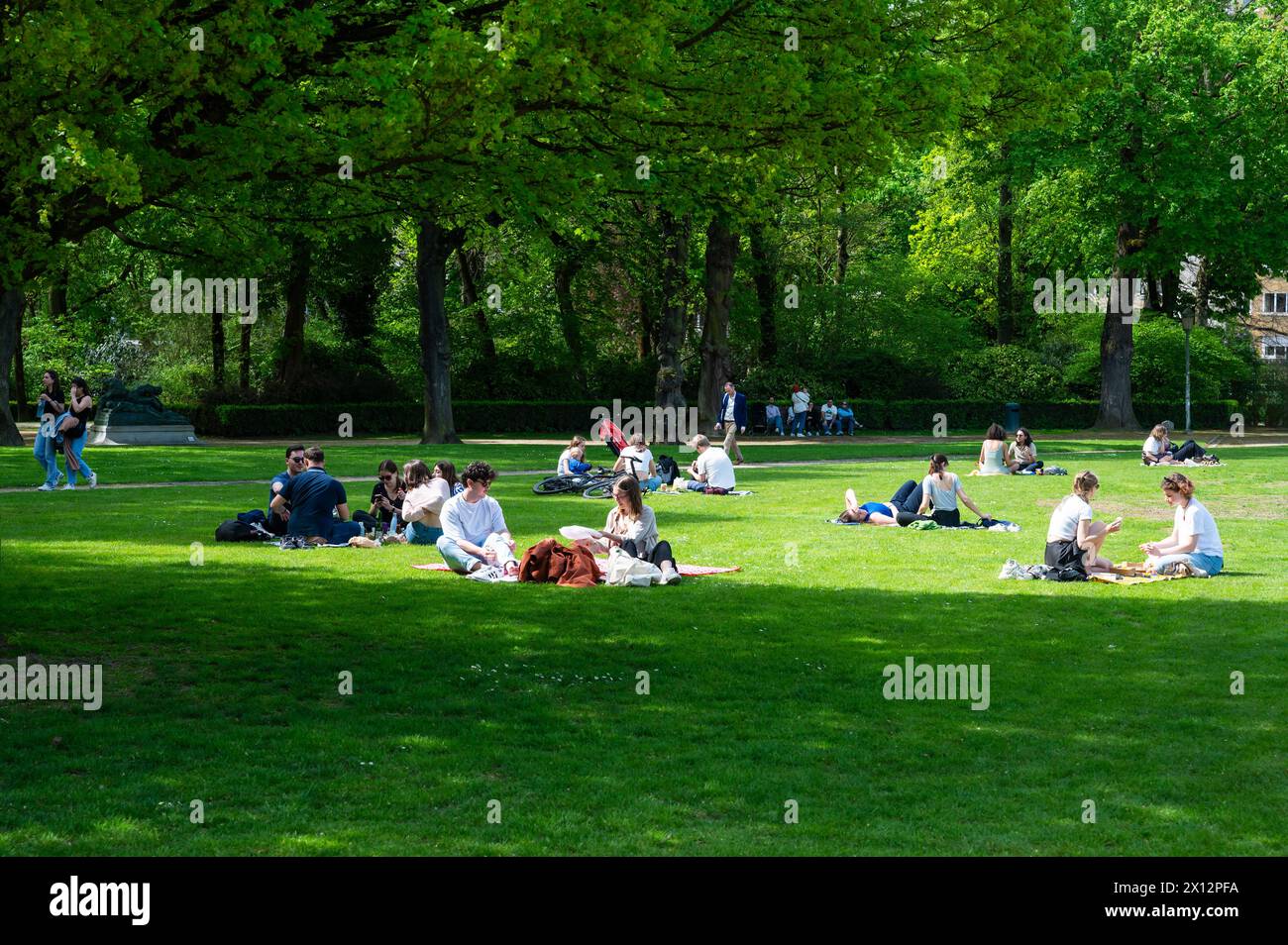 Etterbeek, Bruxelles, Belgique - 13 avril 2024 - jeunes séduisants assis sur la pelouse verte du parc municipal du Cinquentenaire Banque D'Images