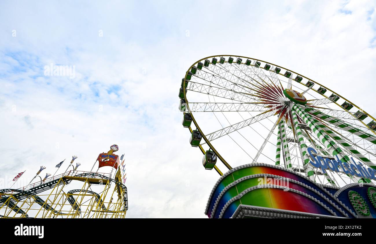 Stuttgart, Allemagne. 15 avril 2024. Une grande roue et des montagnes russes sont installées sur le parc des expositions de Cannstatter Wasen pour le festival du printemps. Le festival de printemps commence le samedi 20 avril, avec plus de 200 showmen, aubergistes et manèges. Crédit : Bernd Weißbrod/dpa/Alamy Live News Banque D'Images