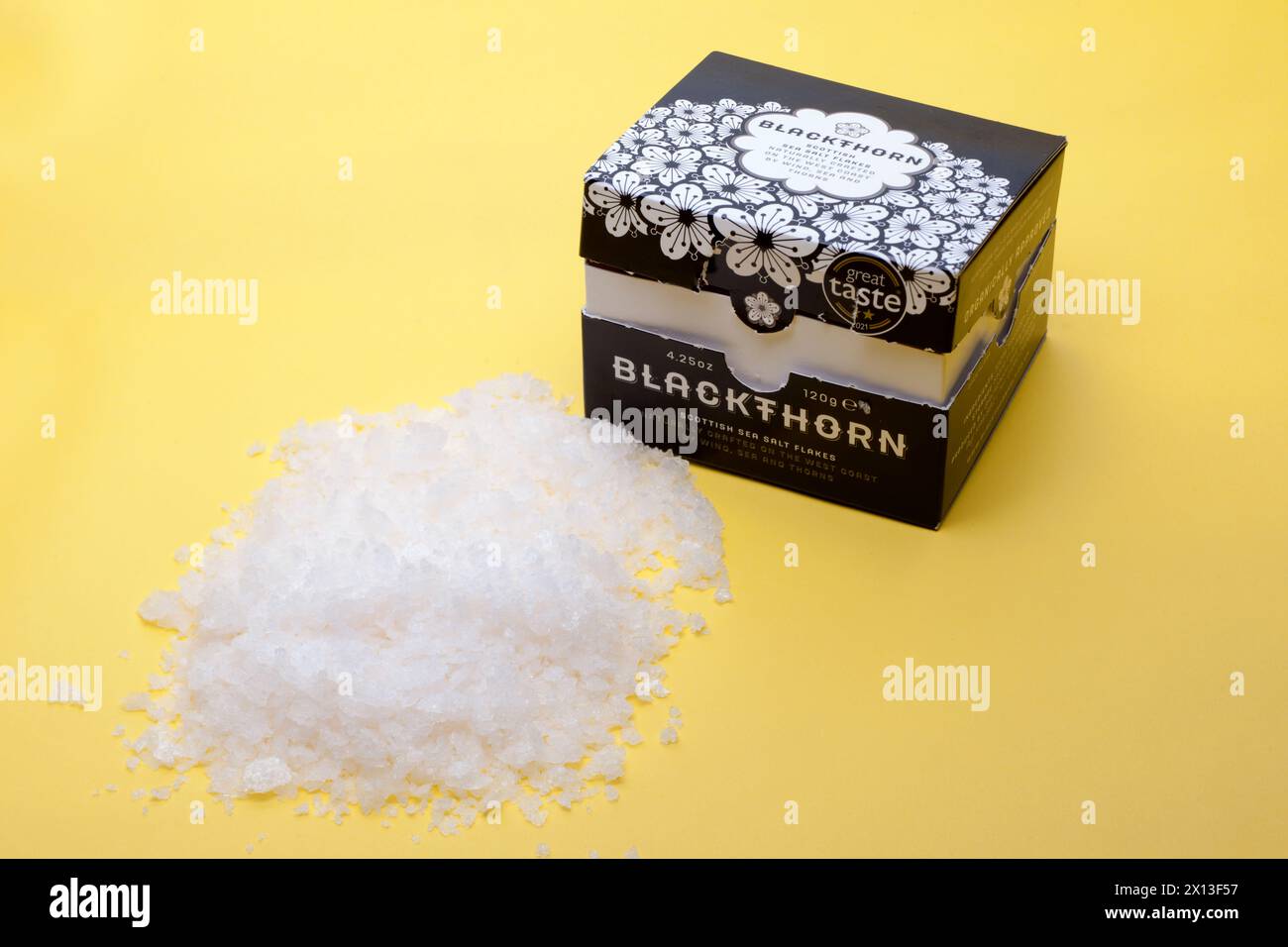 Boîte de 120 grammes de flocons de sel de mer écossais Blackthorn se déversant sur un fond jaune Banque D'Images