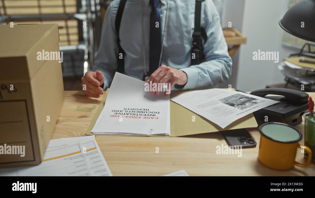 Jeune homme chauve avec une barbe examinant des documents dans un bureau de poste de police, dépeignant un détective au travail à l'intérieur. Banque D'Images