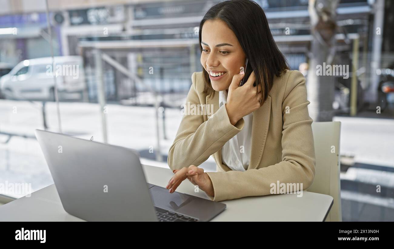 Femme souriante utilisant un ordinateur portable dans un environnement de bureau moderne, représentant la productivité et le style de vie contemporain des affaires. Banque D'Images