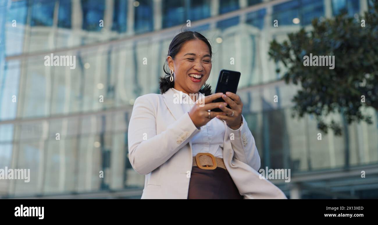 Affaires, téléphone et femme heureuse avec la célébration du poing gagnant dans une ville avec des nouvelles, du succès ou des résultats. Oui, mains et investisseur excité avec l'investissement Banque D'Images