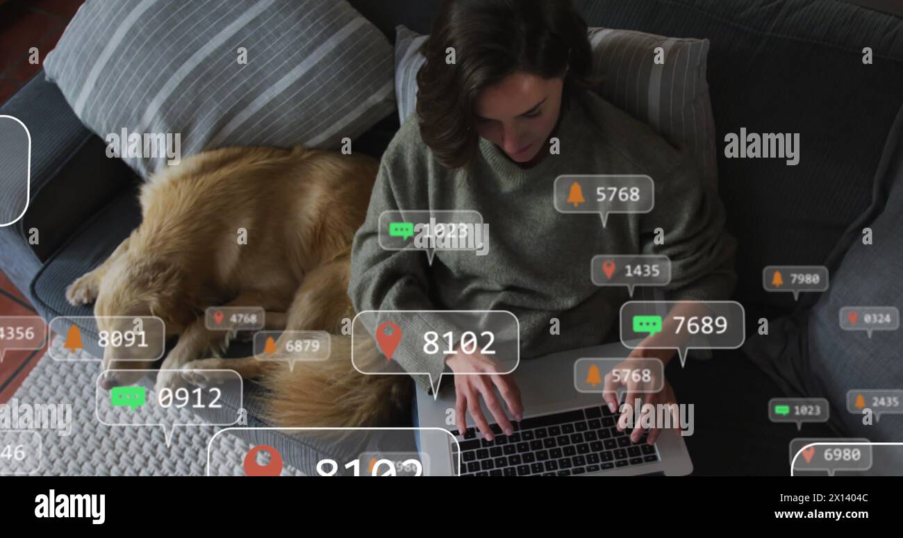 Icônes numériques sur les bulles de parole contre la femme caucasienne utilisant un ordinateur portable tandis que le chien dort sur le canapé Banque D'Images
