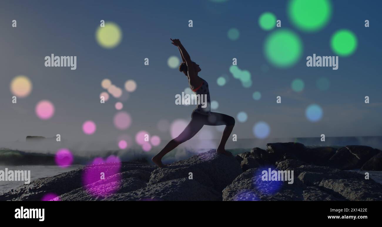 Image de lumières sur une femme caucasienne pratiquant le yoga sur la plage Banque D'Images