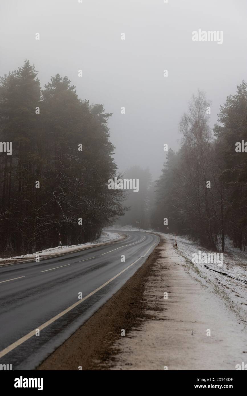 route d'hiver à côté de la forêt en hiver, belle route enneigée pendant le brouillard en hiver Banque D'Images
