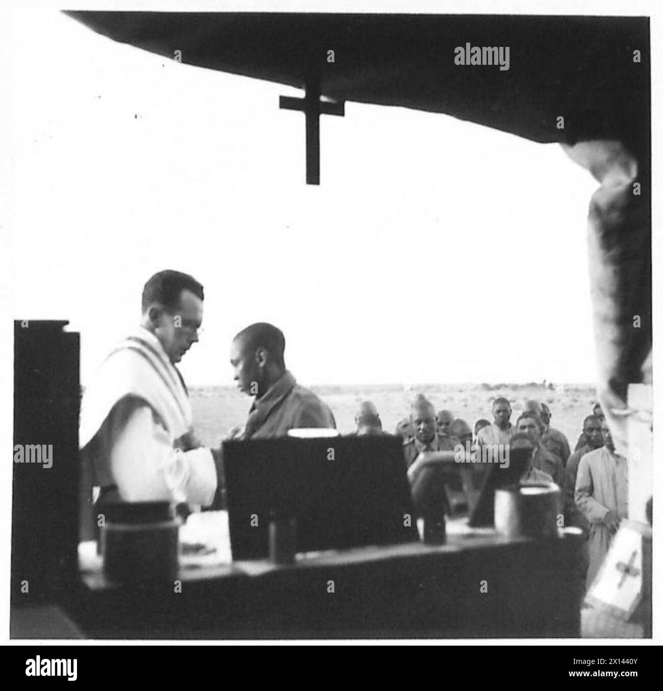 MESSE CATHOLIQUE DANS LE DÉSERT - le prêtre donnant la communion. L'autel est érigé sur un camion de l'armée British Army Banque D'Images