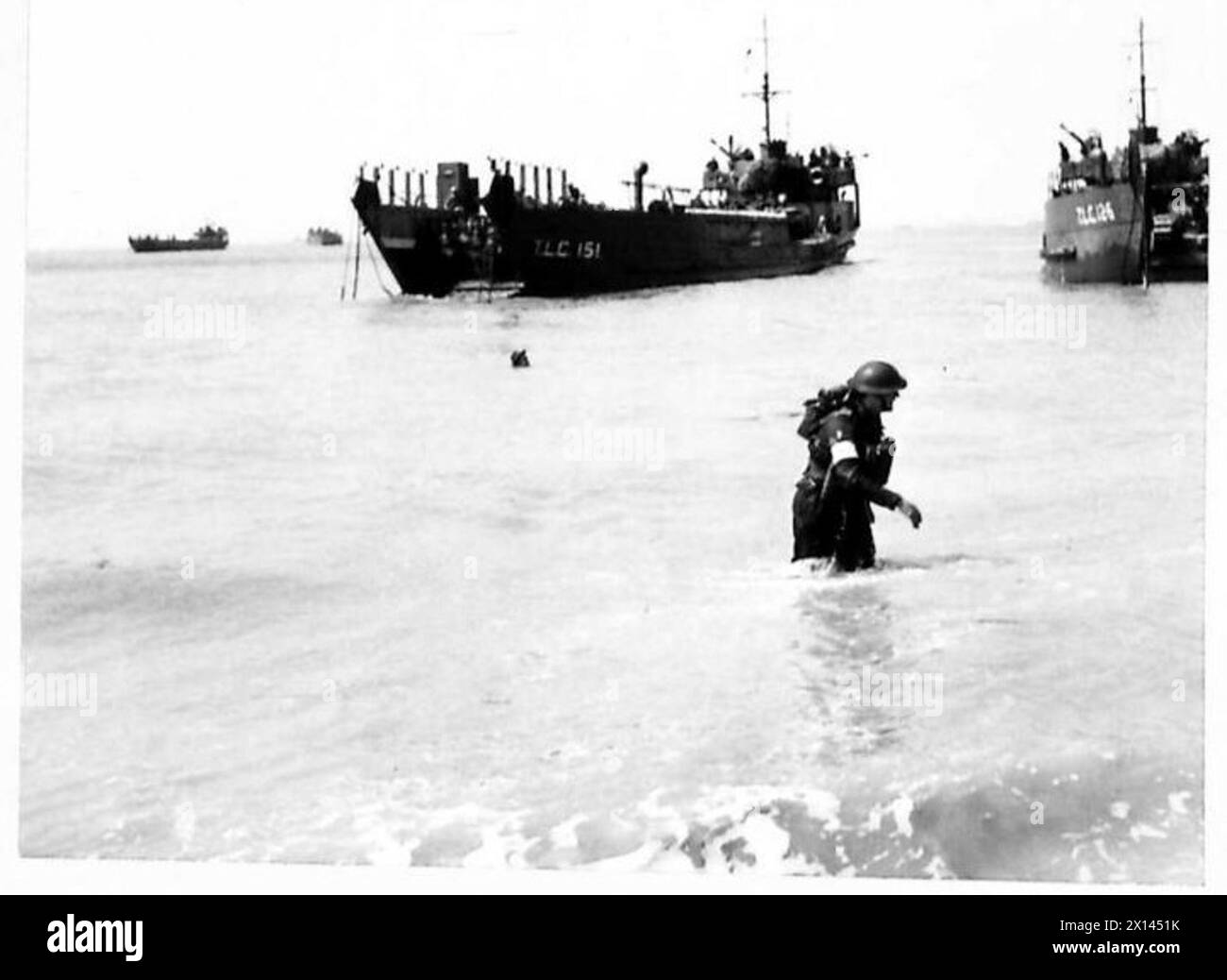 Un MC patère dans les eaux peu profondes tandis que les chars et les troupes sont chargés sur un engin de débarquement pendant les opérations de l'armée britannique. Banque D'Images