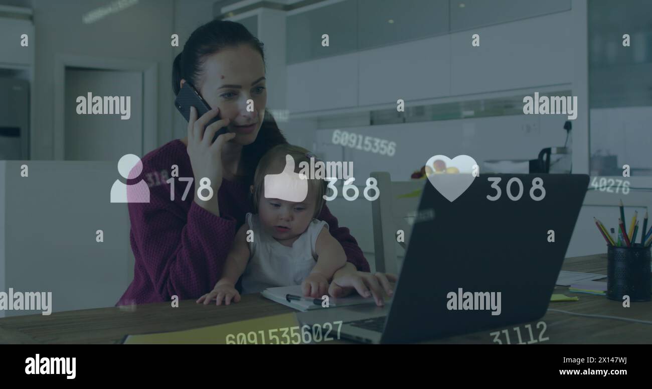 Image des icônes de médias sociaux sur une femme caucasienne avec bébé à l'aide d'un ordinateur portable parlant sur smartphone Banque D'Images